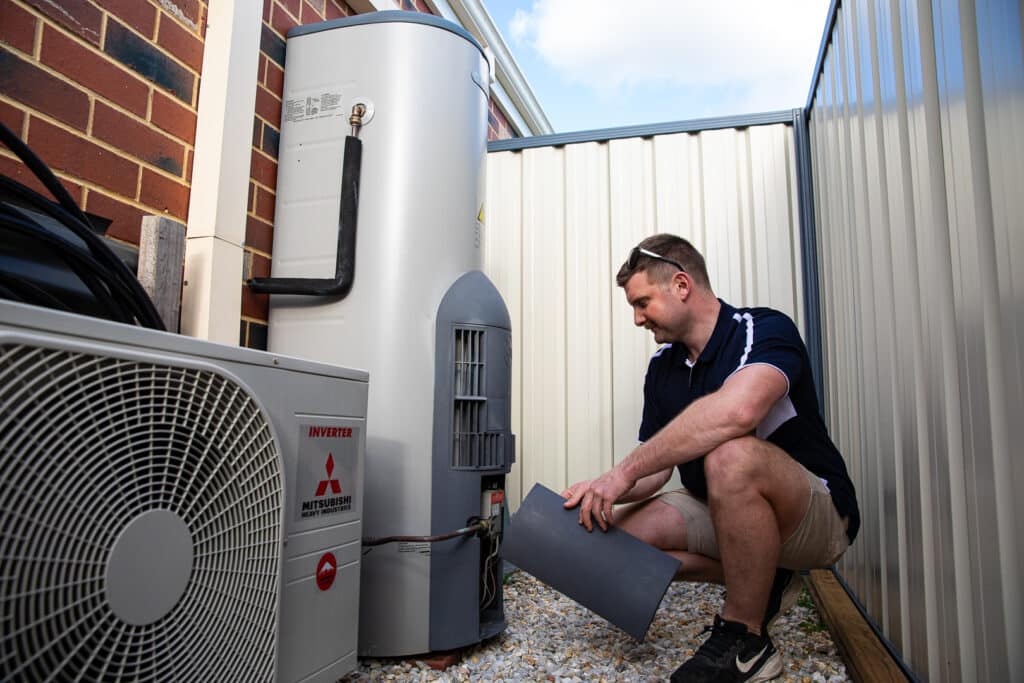 Ausco Plumbing & Gas team member working on outdoor hot water unit