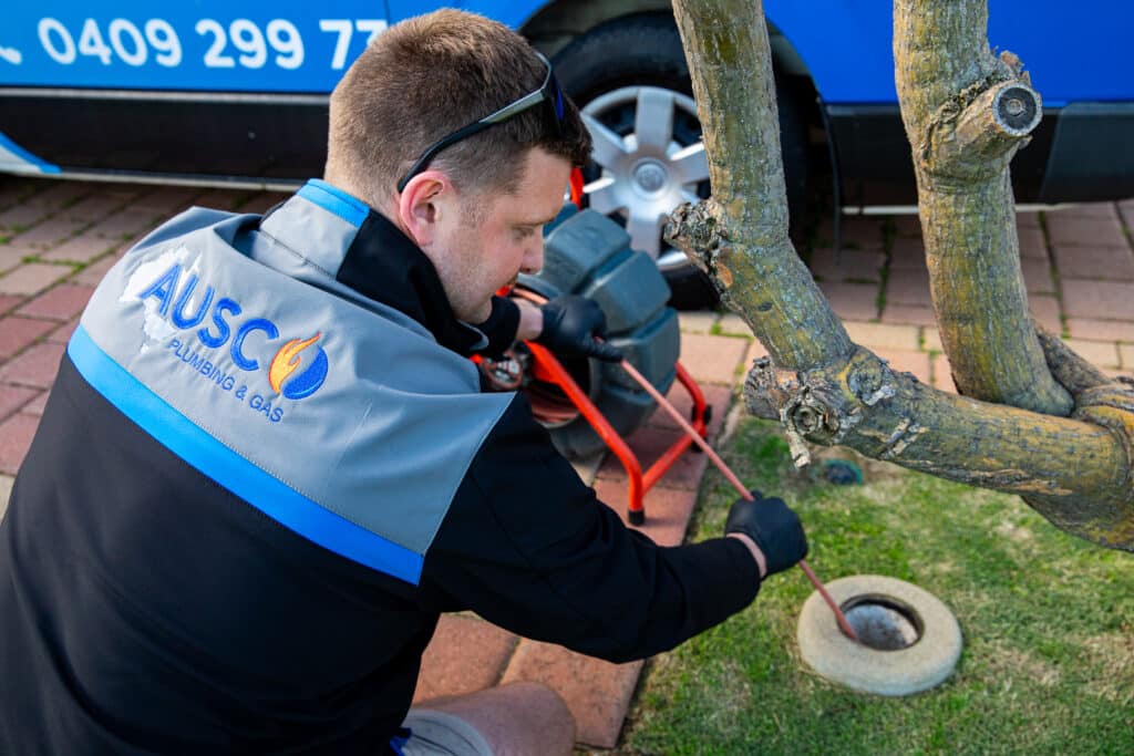Ausco Plumbing & Gas team member unblocking an outdoor drain