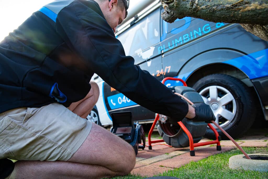Ausco Plumbing & Gas team member unblocking an outdoor drain