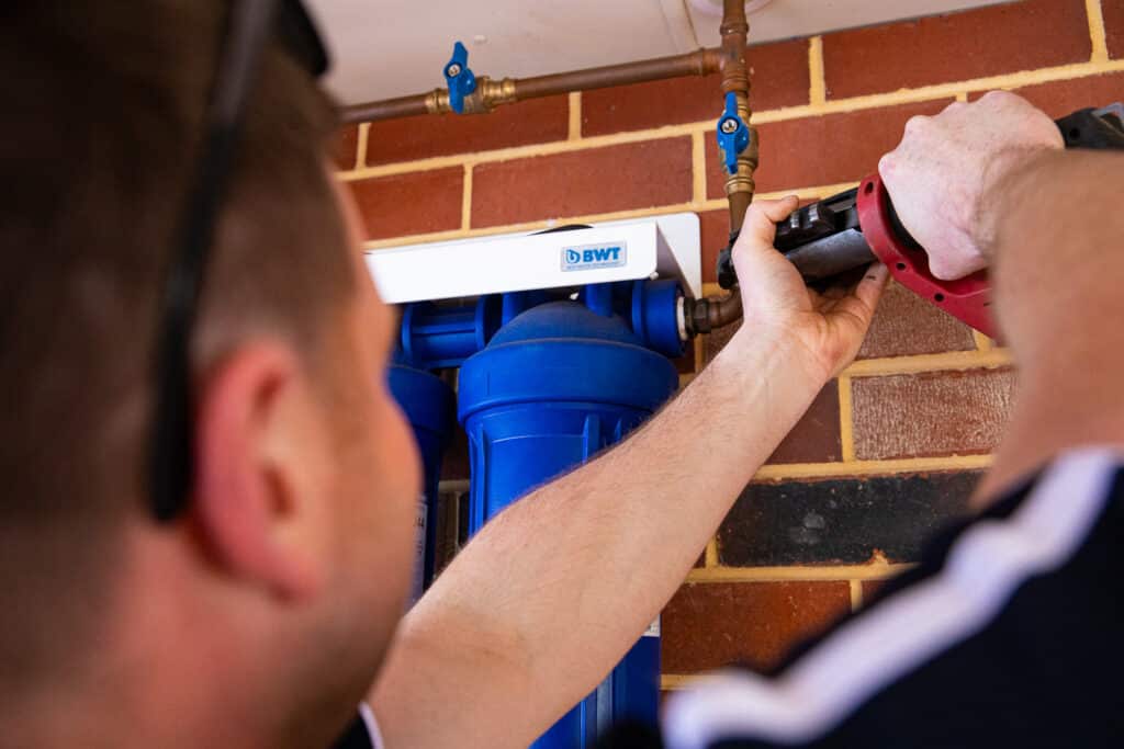 Ausco Plumbing & Gas team member installing a whole house water filtration system